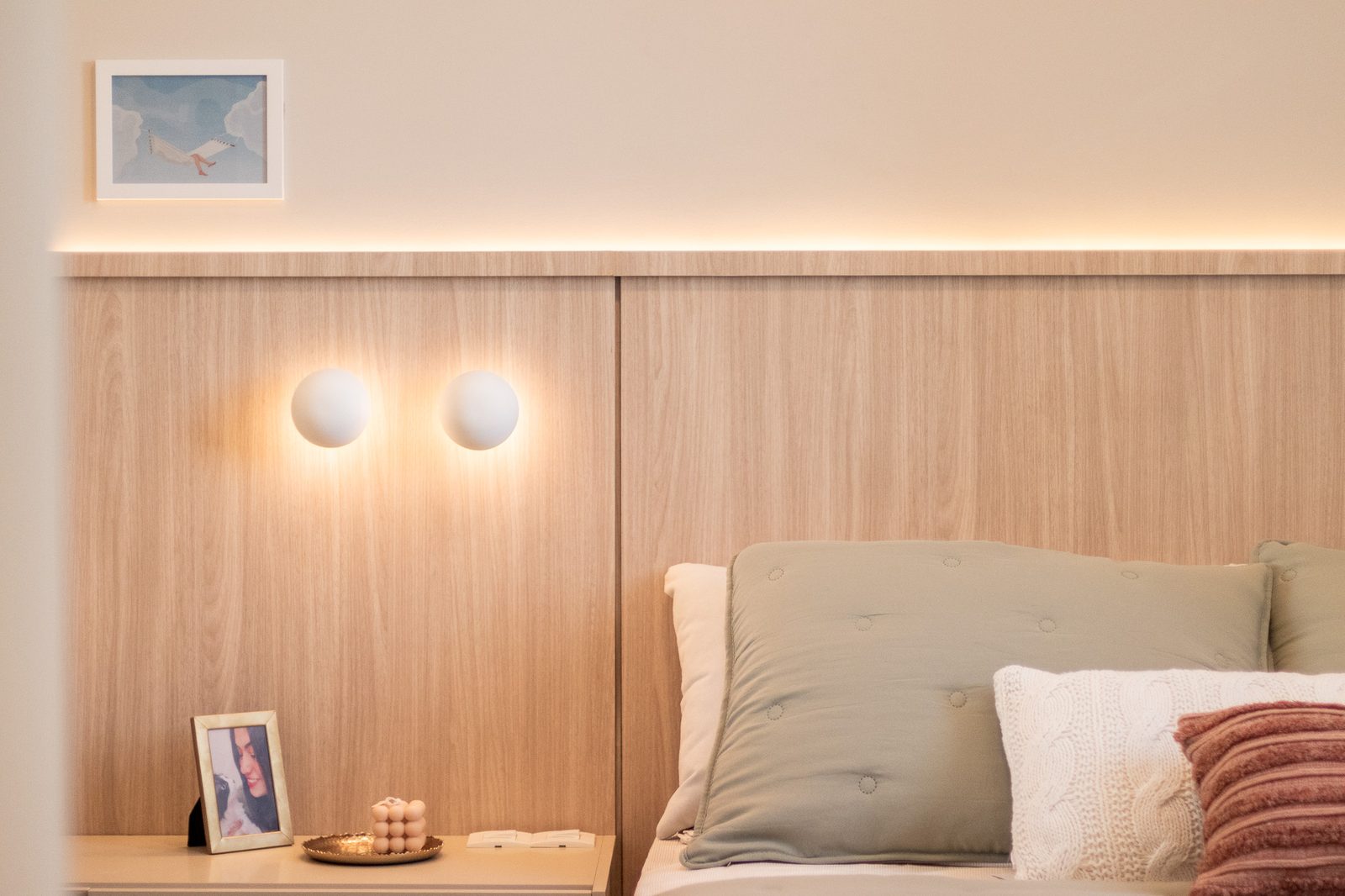 Quarto com cabeceira ripada, arandelas esfera e luz indireta quente
